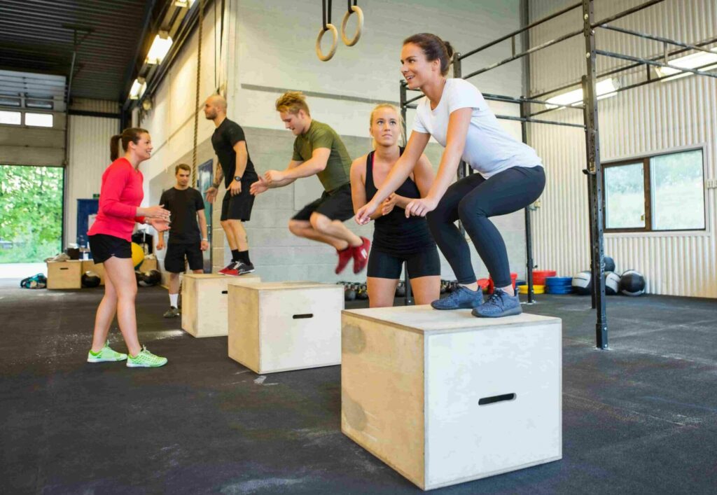 Small group of people doing CrossFit style box jumps