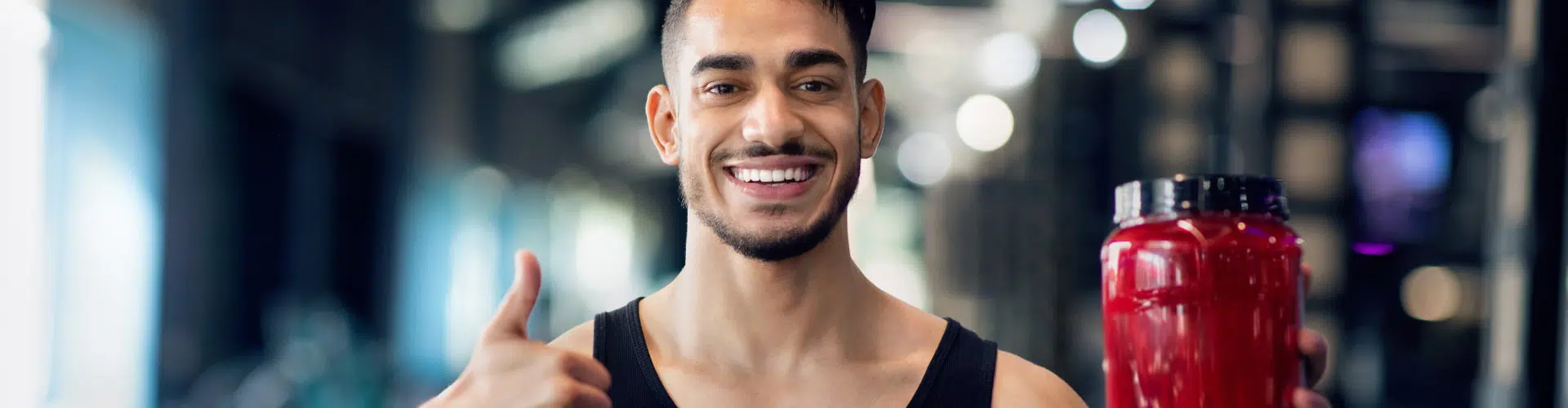 Man giving thumbs up while holding drink made with protein powder