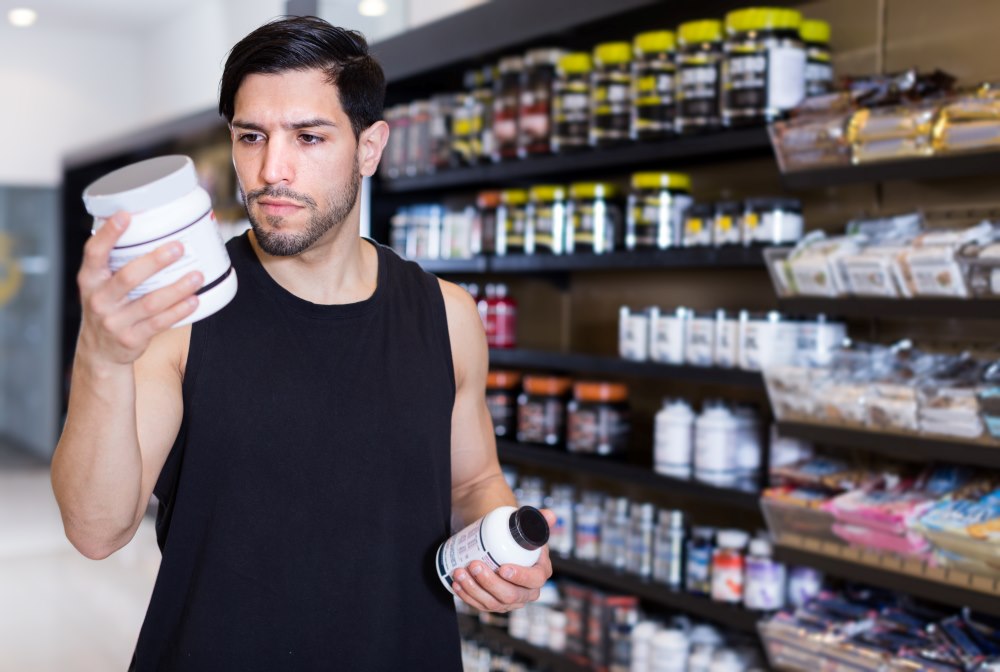 Man reading product labels in middle of health store