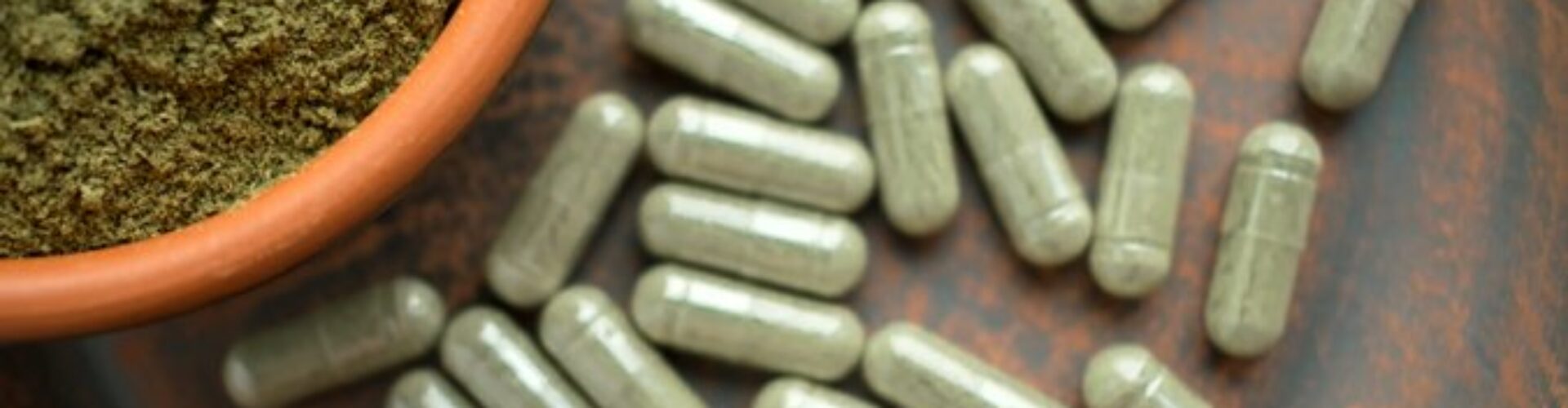 A few Kratom capsules standing on a surface.