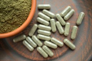 A few Kratom capsules standing on a surface.