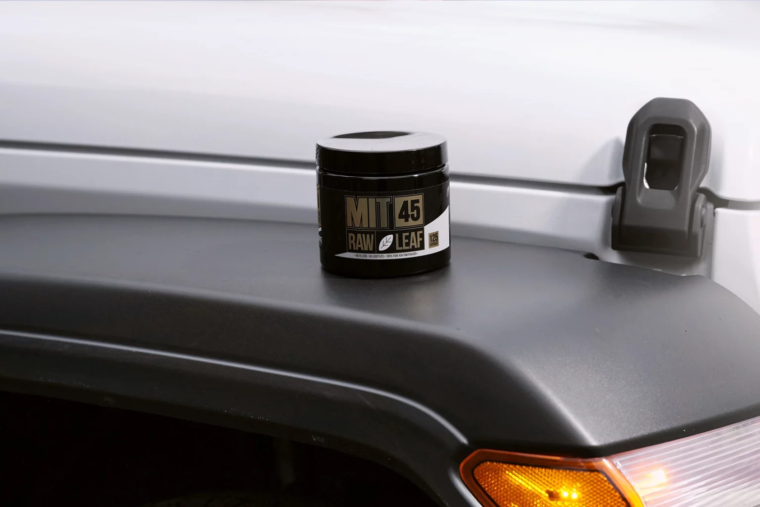 Canister of MIT45 white vein capsules on car fender