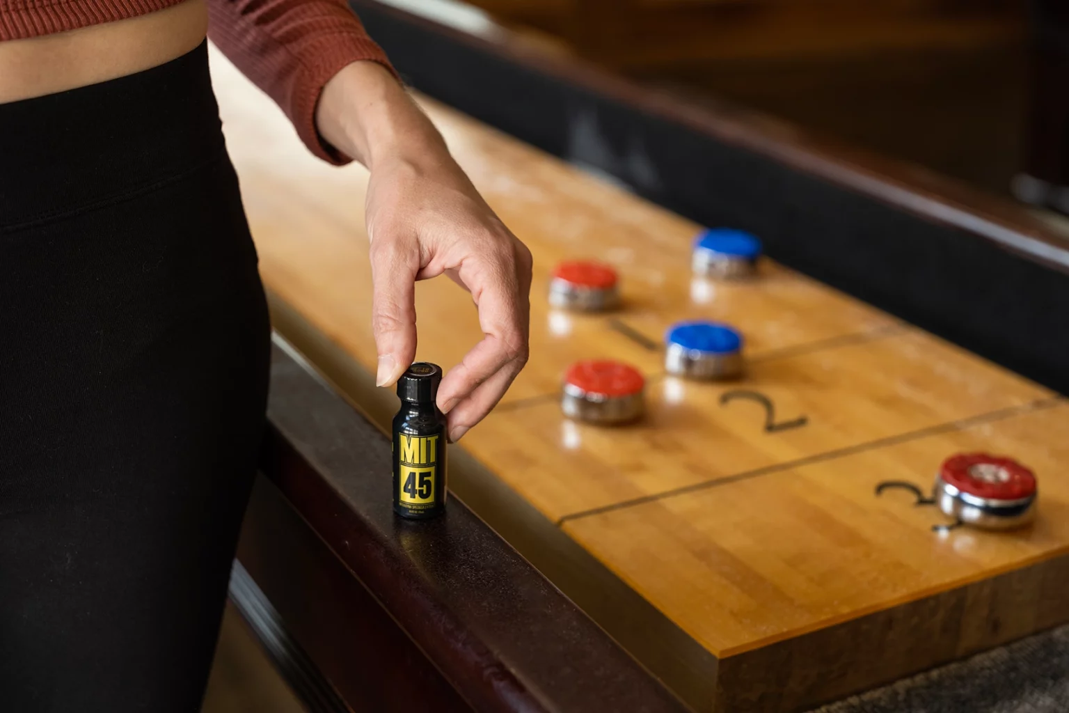 woman holding MIT45 Gold extract over shuffleboard table
